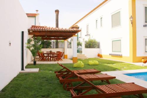 une terrasse avec des tables et des chaises en bois et une piscine dans l'établissement Villa Reis - Boutique House, à Golegã