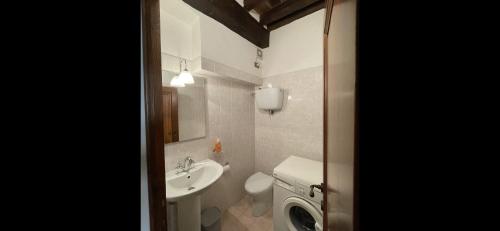 een witte badkamer met een wastafel en een toilet bij PULCINELLA appartamento tipico centro storico in Montepulciano