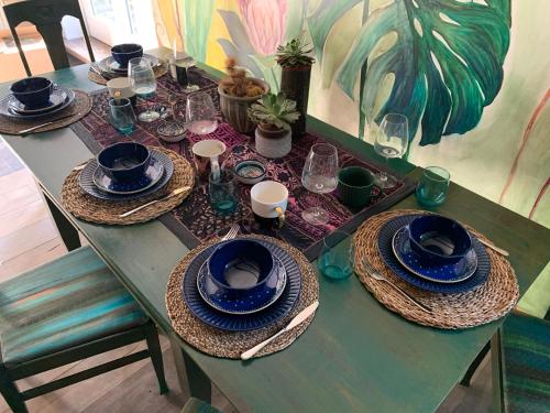 a green table with blue plates and glasses on it at Frica Ludvika Garden Apartment in Liepāja