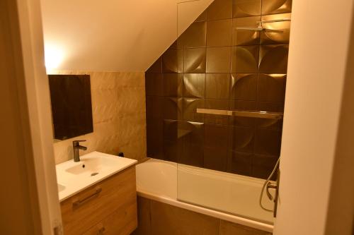 La salle de bains est pourvue d'un lavabo et d'une baignoire. dans l'établissement La maison penchée, à Rosny-sous-Bois