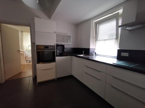 a large kitchen with white cabinets and a window at Ulm 2-room Apartment near university & city Centre in Ulm
