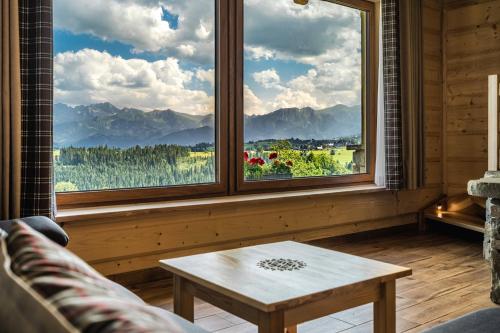 a living room with a table and a large window at Osada Wierchlove Domki in Bustryk