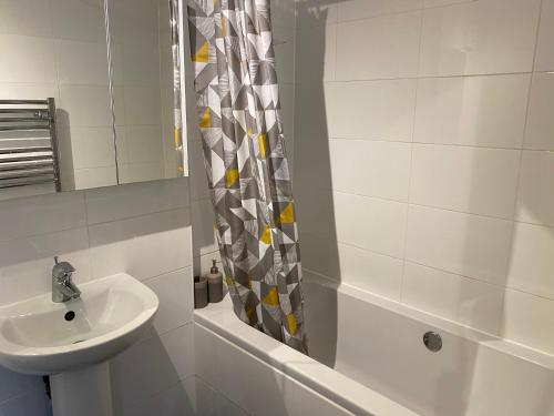 y baño blanco con lavabo y ducha. en Marie’s Serviced Apartment 2 bed Olivier Court, en Bedford