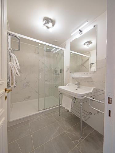 a white bathroom with a shower and a sink at Hôtel de Boisgelin in Pléhédel