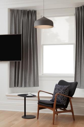 a living room with a chair and a flat screen tv at Victorian Hotel in Vancouver