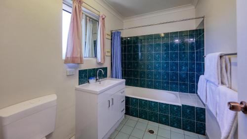 a bathroom with a sink and a tub and a toilet at Townview Motel in Mount Isa