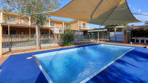 a large blue swimming pool with a large umbrella at Townview Motel in Mount Isa