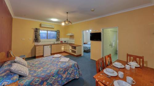 a bedroom with a bed and a table and a kitchen at Townview Motel in Mount Isa