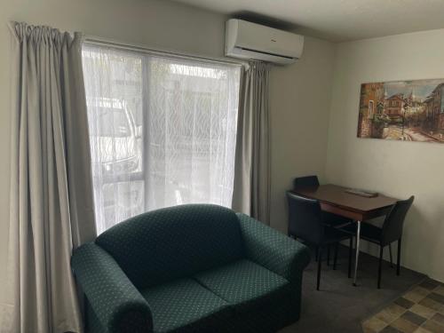 a living room with a chair and a table and a window at Cranford Cottages and Motel in Christchurch