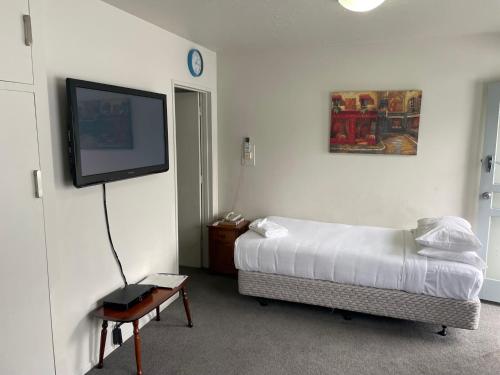 a bedroom with a bed and a flat screen tv at Cranford Cottages and Motel in Christchurch