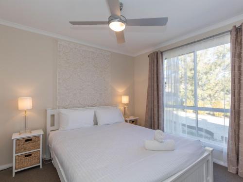 a bedroom with a white bed and a large window at St Helenas 5 Twynam Street in Jindabyne