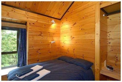 a room with a bed in a wooden cabin at Dakune Lodge in Ohakune