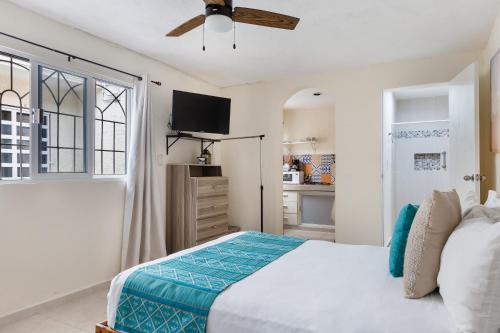 a white bedroom with a bed and a tv at El depa de Acuario in Cancún