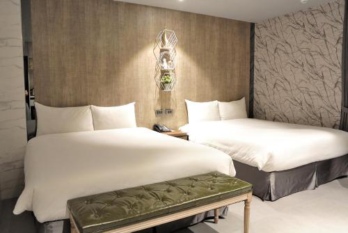 duas camas num quarto de hotel com lençóis brancos em K HOTEL em Taichung