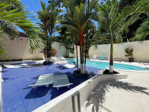 a swimming pool with palm trees and lounge chairs at Millenium Manuel Antonio Park and beach in Manuel Antonio