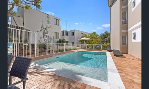 a swimming pool with two chairs next to a building at Aqua Promenade Beachfront Holiday Apartments in Sunrise Beach