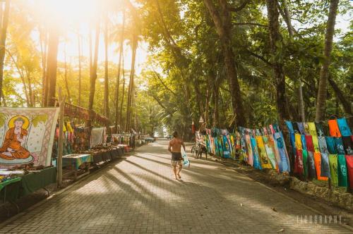 a man walking down a street next to a market at Boutique Rooms River Front at La Junta in Dominical
