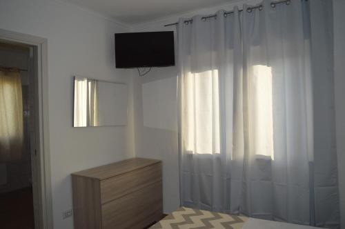 a room with a television and a dresser and a window at Affittacamere Sos Ninnitteddos in Torpè
