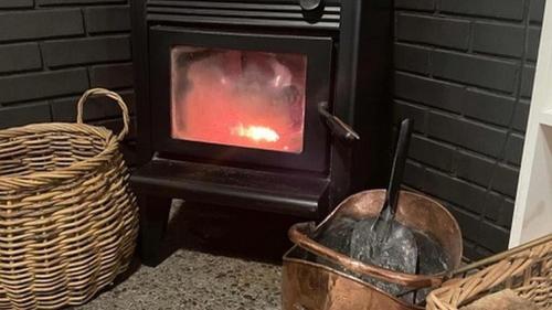 a stove with a fire in it next to a basket at Tongariro Adventures The Lodge in Kuratau