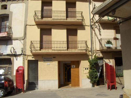 an apartment building with two balconies and red chairs at Apartaments la Fabrica in Horta de San Joan