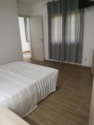 a bedroom with a white bed and a tile floor at Affittacamere Sos Ninnitteddos in Torpè