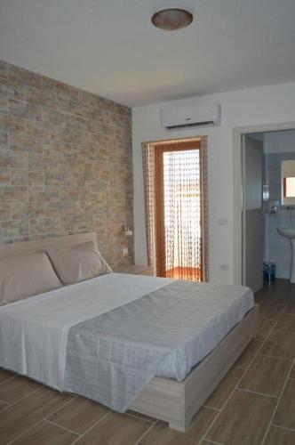 a bedroom with a bed and a brick wall at Affittacamere Sos Ninnitteddos in Torpè