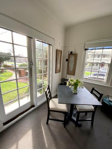 a dining room with a table and chairs and windows at East Melbourne City Studio - Amazing Location & Sunny Charm in Melbourne