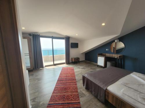 a bedroom with a bed and a desk and a large window at Olimpia Hotel in Fethiye