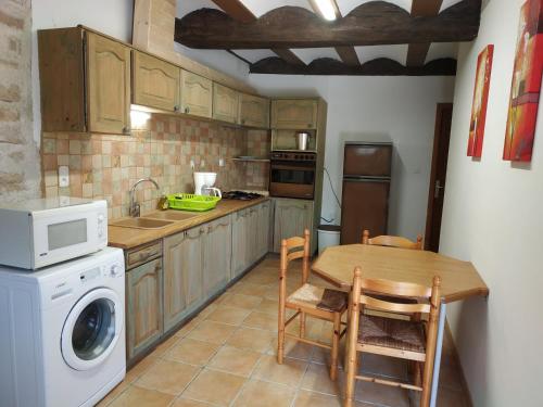 une cuisine avec une table et une machine à laver dans l'établissement GÎTE DU COLOMBIER, à Vernoux