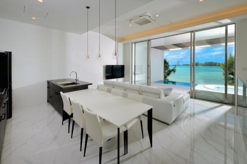 恩納的住宿－Villa VALIOSA ON THE BEACH，厨房以及带白色桌椅的用餐室。