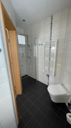 a white bathroom with a shower and a toilet at Avenue Das Gästehaus in Chemnitz