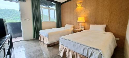 a hotel room with two beds and a window at Jinhue Hotel in Luye