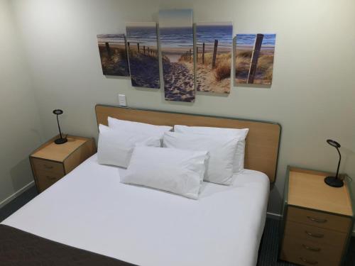 a bedroom with a bed with four paintings on the wall at Bay of Islands Gateway Motel & Apartments in Paihia