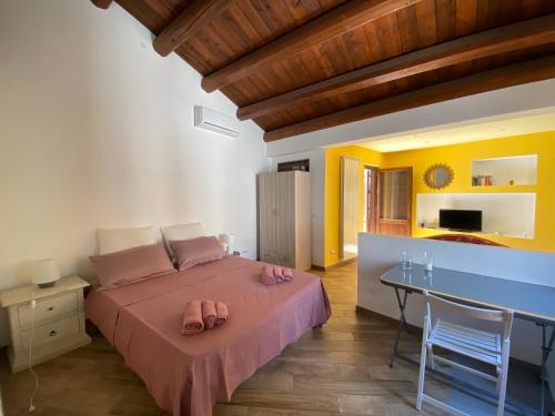 Schlafzimmer mit einem Bett mit rosa Bettwäsche und einem Tisch in der Unterkunft Monolocale Sant'Andrea in Palermo