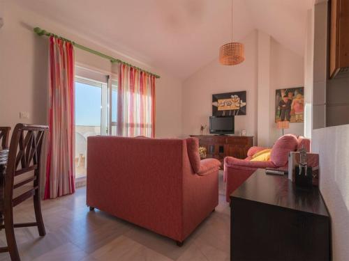 a living room with a red couch and a table at Fantástico ático con terraza, garaje, wifi, con todo para playa, piscina y casa y no facturar maletas! in El Portil