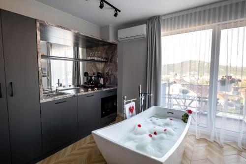 uma banheira branca na casa de banho com um lavatório em Студио с вана и гледка в "The House" с Термална зона em Velingrad