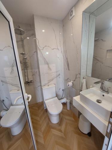 a white bathroom with a toilet and a sink at Студио с вана и гледка в "The House" с Термална зона in Velingrad
