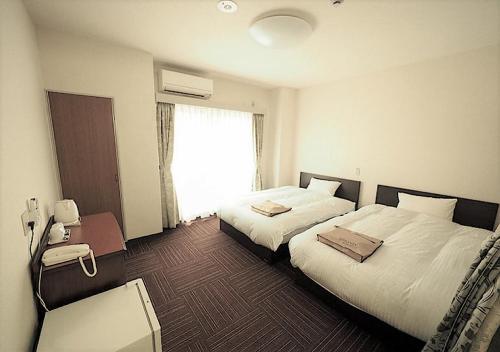 大阪市にあるビジネスホテル アーバンティ西九条のベッド2台と窓が備わるホテルルームです。