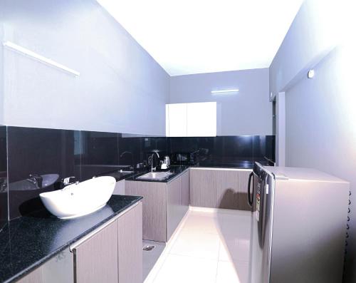 a large kitchen with a sink and a refrigerator at Transit Suites by GrandWest in Nedumbassery