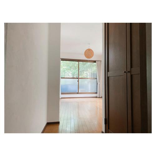 an empty room with a large window and a hallway at ゲストハウスよるよなか in Nagoya