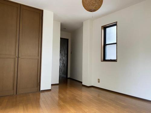 an empty room with a door and a window at ゲストハウスよるよなか in Nagoya