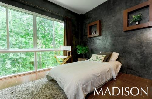 a bedroom with a bed and a large window at Madison Hotel in Nakhon Si Thammarat