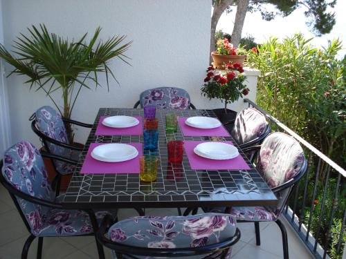 a table and chairs on a balcony with a table and plates at Sea Star Apartment in Sutivan