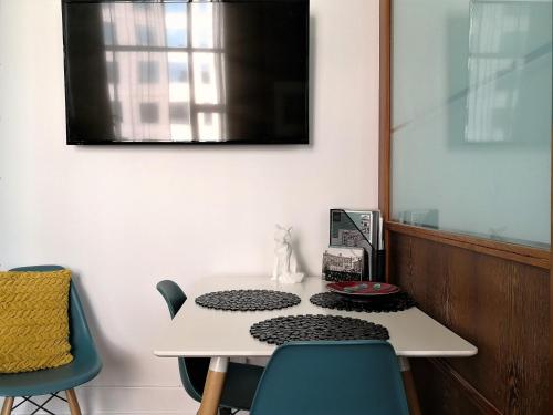 a white table with chairs and a television on a wall at Private apartments in a Landmark Heritage Building in Auckland