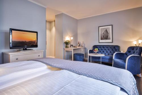 um quarto de hotel com uma cama e uma TV de tela plana em Sylthotel Raffelhüschen Garni em Westerland
