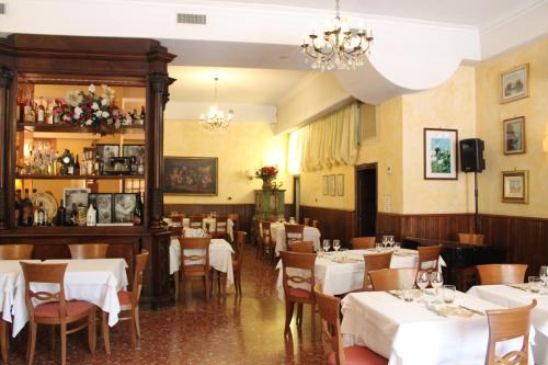 a restaurant with white tables and chairs and a chandelier at Hotel La Locanda Del Borgo in Casal Monastero