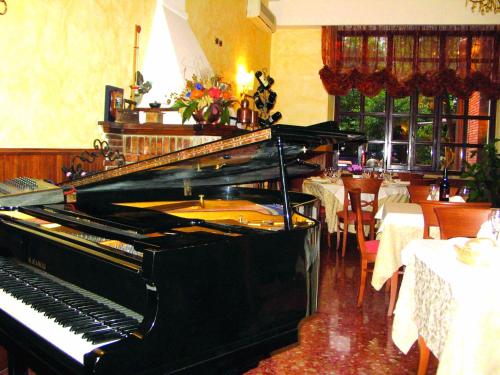 a piano in a restaurant with a dining room with tables at Hotel La Locanda Del Borgo in Casal Monastero