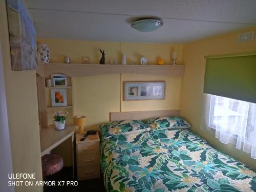 a small bedroom with a bed and a dresser at Gina's Static caravan,118 Sandsgate in Hemsby