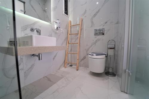 a white bathroom with a sink and a toilet at Casa Arkoudas in Parga