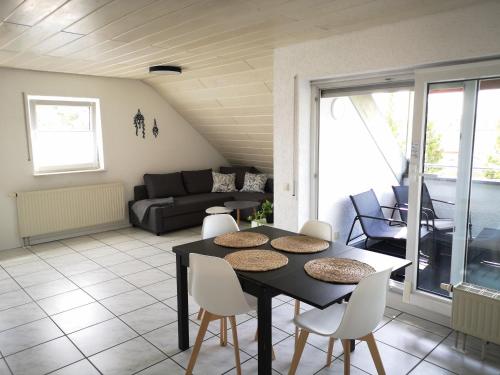 uma sala de estar com uma mesa e cadeiras e um sofá em Familienfreundliche Ferienwohnung mit Wohlfühlbalkon und kostenlosem Parkplatz nahe Messe und Bodensee em Meckenbeuren